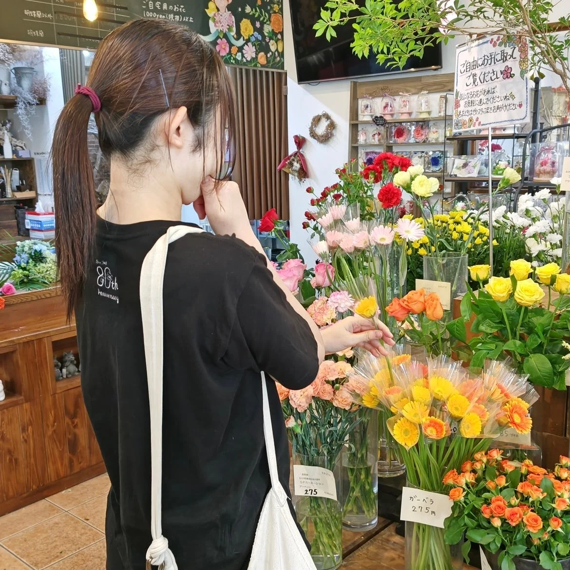 女性が花屋で色とりどりの花を眺めている